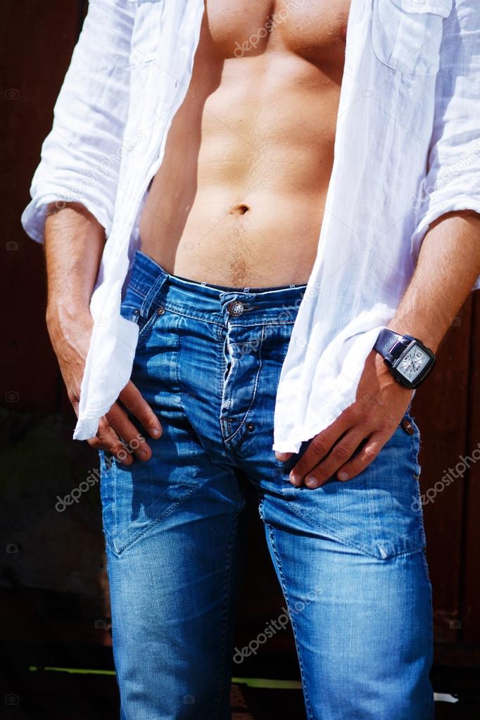 Close-up portrait of a mans body, dressed in jeans and white shirt, with a clock on hand.