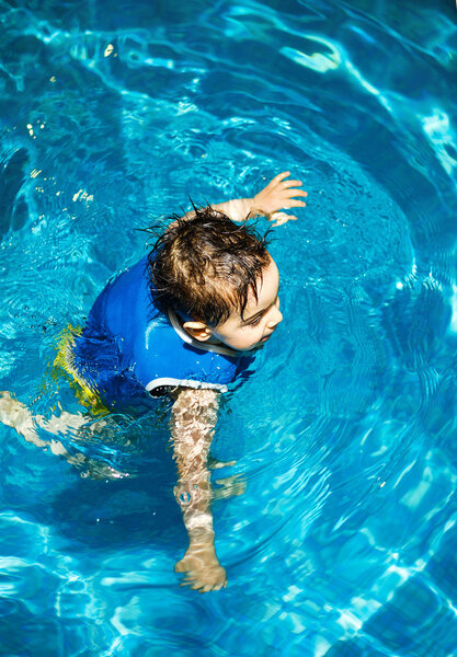 Мальчик с надувным плавательным жилетом в бассейне
