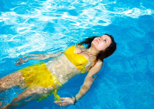 Porträt einer jungen Frau, die sich in einem Swimmingpool entspannt. Schwimmen im Pool und gelben Badeanzug. Kopierraum. — Stockfoto