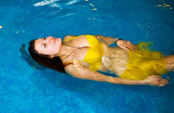 Porträt einer jungen Frau, die sich in einem Swimmingpool entspannt. Schwimmen im Pool und gelben Badeanzug. Kopierraum. — Stockfoto