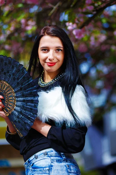 Hermosa chica con flores y glamour de piel blanca y ventilador negro — Foto de Stock