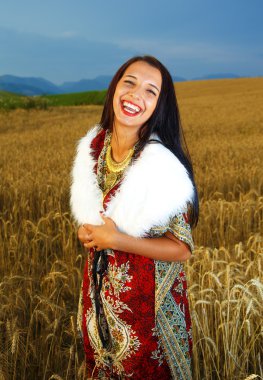 Gülümseyen gün batımı ile buğday alan üzerinde duran süs elbise ile genç kadın. Doğal arka plan..