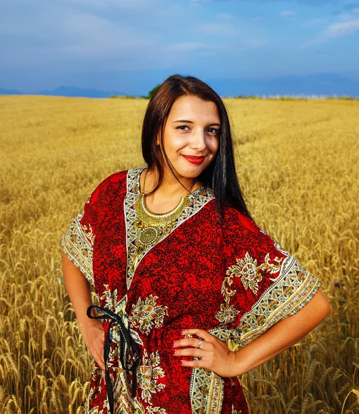 Leende ung kvinna med prydnads klänning stående på en vete — Stockfoto