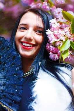 Güzel bir sakura çiçeği kokan genç bir kadın, mor çiçekler. Bahar Büyüsü.