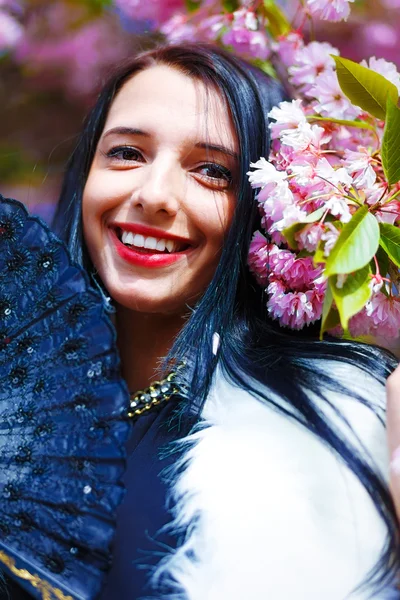 Güzel bir sakura çiçeği kokan genç bir kadın, mor çiçekler. Bahar Büyüsü.