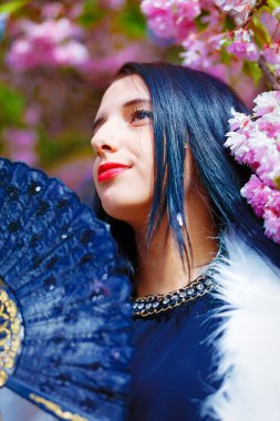 Güzel bir sakura çiçeği kokan genç bir kadın, mor çiçekler. Bahar Büyüsü.