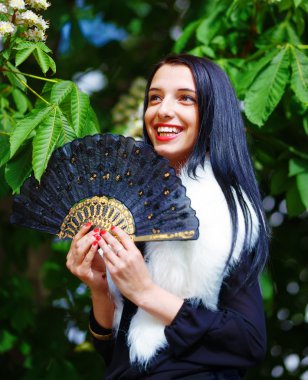 Smiling young woman smelling a beautiful  blossom, white flowers. Spring Magic, and beautiful ornamental fan. Flower background.