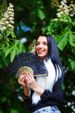 Smiling young woman smelling a beautiful  blossom, white flowers. Spring Magic, and beautiful ornamental fan. Flower background.