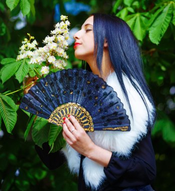 Smiling young woman smelling a beautiful  blossom, white flowers. Spring Magic, and beautiful ornamental fan. Flower background.