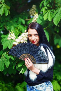 Beautiful Girl with flowers, posing next to blooming magical spring rosa sakura flowers. Flower background