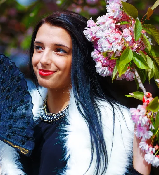 Güzel bir sakura çiçeği kokan genç bir kadın, mor çiçekler. Bahar Büyüsü.