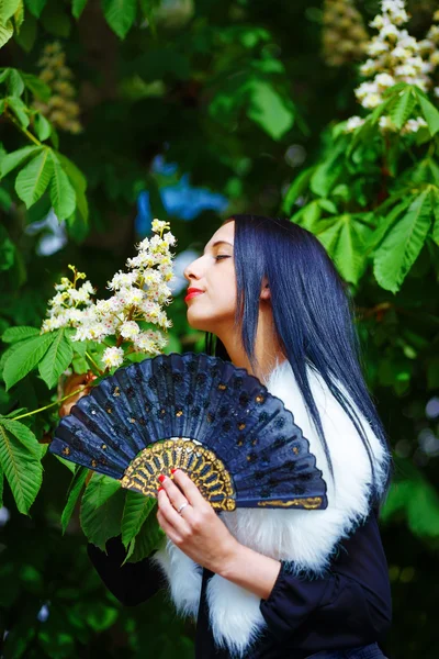 Smiling young woman smelling a beautiful  blossom, white flowers. Spring Magic, and beautiful ornamental fan. Flower background. — Stock Photo, Image