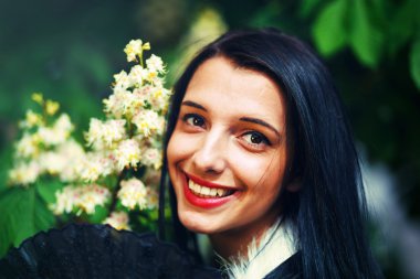 Smiling young woman smelling a beautifull Spring Magic, and beautiful ornamental fan and white fur. Flower background.
