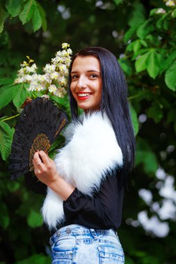 Smiling young woman smelling a beautifull Spring Magic, and beautiful ornamental fan and white fur. Flower background.