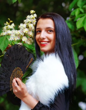 Smiling young woman smelling a beautifull Spring Magic, and beautiful ornamental fan and white fur. Flower background.