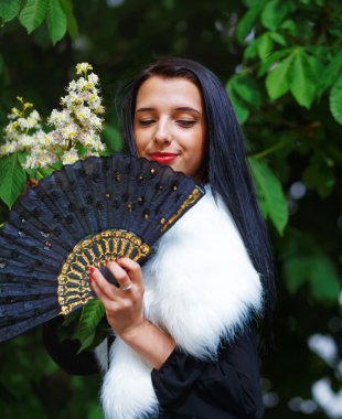 Smiling young woman smelling a beautifull Spring Magic, and beautiful ornamental fan. Flower background.