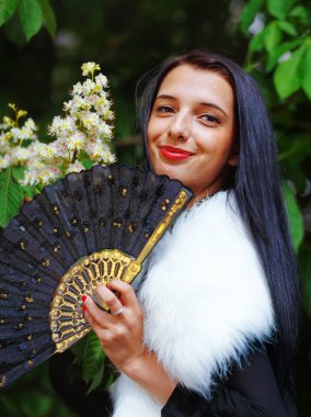 Smiling young woman smelling a beautifull Spring Magic, and beautiful ornamental fan. Flower background.