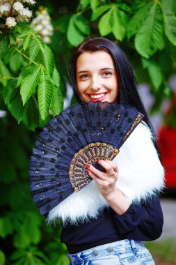 Smiling young woman smelling a beautiful sakura blossom, purple flowers. Spring Magic, and beautiful ornamental fan. Flower background.