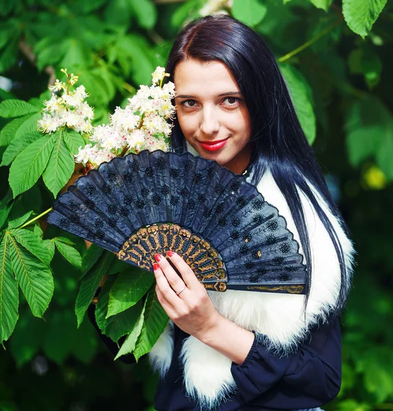 Smiling young woman smelling a beautiful  blossom, white flowers. Spring Magic, and beautiful ornamental fan. Flower background. — Stock Photo, Image