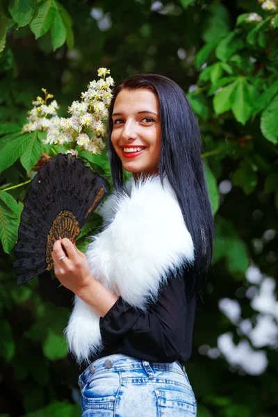 Smiling young woman smelling a beautifull Spring Magic, and beautiful ornamental fan and white fur. Flower background. — Stock Photo, Image