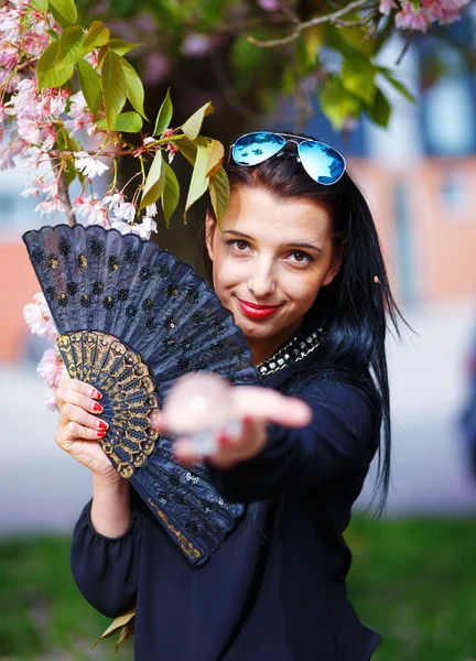 Young woman smelling a beautiful sakura blossom, purple flowers. Spring Magic, Magical Glass sphere in hand and beautiful ornamental fan — Stock Photo, Image