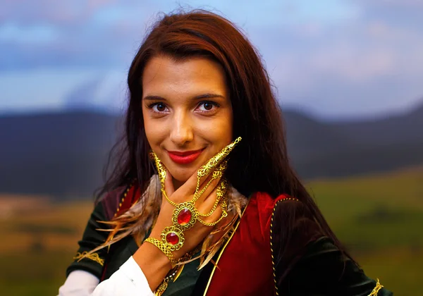 Lächelnde junge Frau mit dekorativem Kleid und Handschmuck und Fingerkiefer natürlichen Hintergrund — Stockfoto