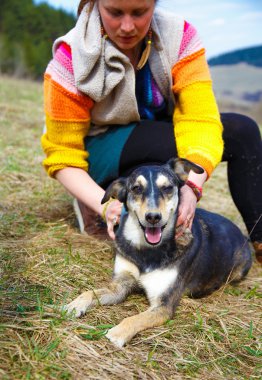 Woman brushing her dog in spring meadows. Smiling Dog