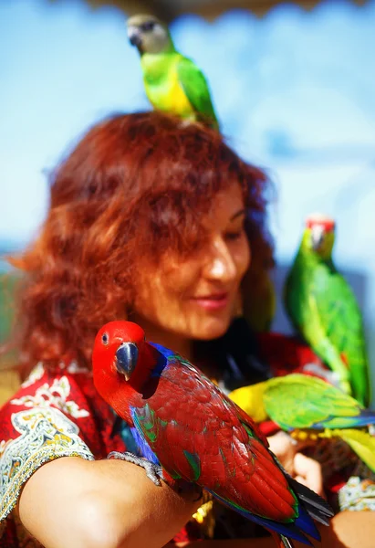 Молода жінка в декоративній сукні і красиві золоті прикраси з кольоровими папугами — стокове фото