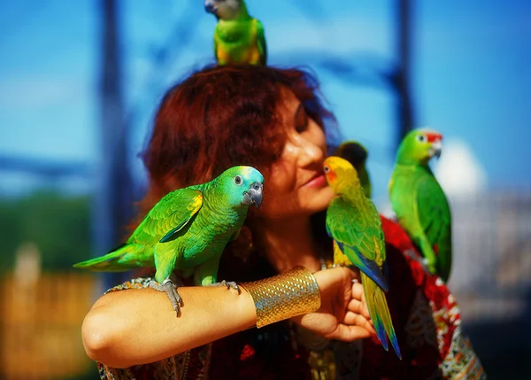 Young woman in ornamental dress and beautiful gold jewelry with a color parrots — Stock Photo, Image
