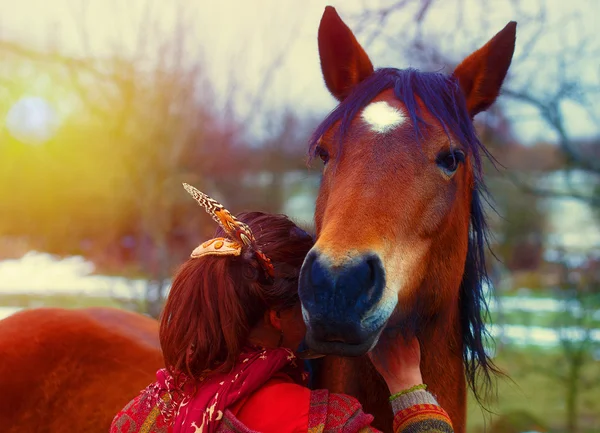 Mulher retrato e cavalo ao ar livre. mulher abraçando um cavalo e tem pena no cabelo. Na luz sul — Fotografia de Stock