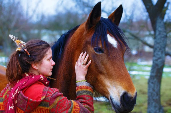 Mulher retrato e cavalo ao ar livre. mulher abraçando um cavalo e tem pena no cabelo . — Fotografia de Stock
