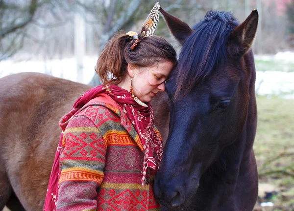Portrait femme et cheval en plein air. femme étreignant un cheval et a une plume dans ses cheveux — Photo