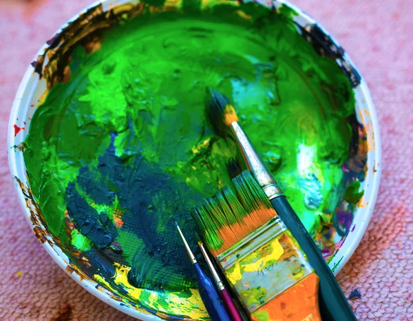 Pinceles a la paleta de pintura con colores. en la alfombra —  Fotos de Stock