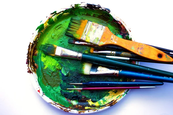 Pinceles a la paleta de pintura con colores sobre fondo blanco — Foto de Stock