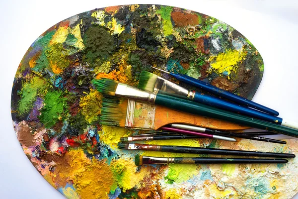 Pinceles a la paleta de pintura con colores sobre fondo blanco — Foto de Stock