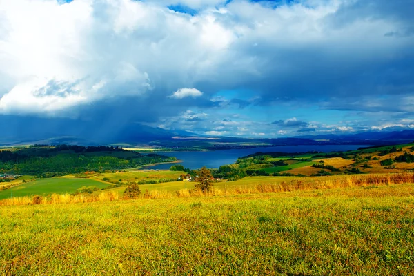 Prachtig landschap, groene en gele weide en meer met berg op de achtergrond. Slowakije, Midden-Europa. — Stockfoto