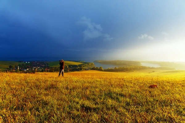 Paisagem de verão idílica com lago e prado verde e amarelo. Europa Central. Com fotógrafo e cão . — Fotografia de Stock