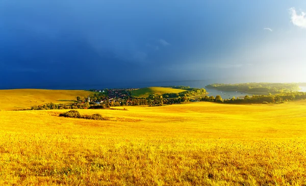 Paisaje de color con nubes de tormenta, prado verde y amarillo y lago . —  Fotos de Stock