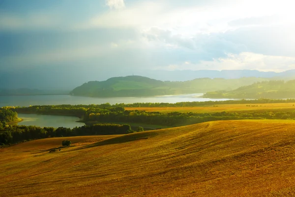 Прекрасний пейзаж, зелена і жовта лука і озеро з горою на задньому плані. Словаччина, Центральна Європа. — стокове фото