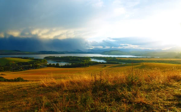 Paisagem bonita, prado verde e amarelo e lago com aldeia. Eslováquia, Europa Central. — Fotografia de Stock