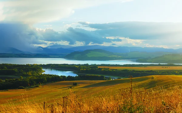 Güzel manzara, yeşil ve sarı çayır ve arka planda dağ olan göl. Slovakya, Orta Avrupa. — Stok fotoğraf