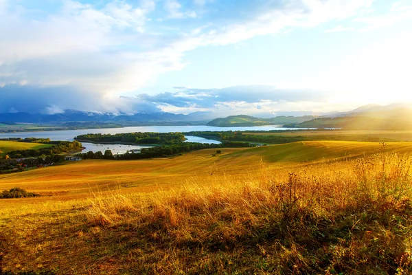 Beautiful landscape, green and yellow meadow and lake with mountains on background . Slovakia, Central Europe. — Stock Photo, Image