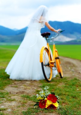 bride on orange bike in beautiful wedding dress with lace in landscape. with wedding bouquet. wedding concept. clipart
