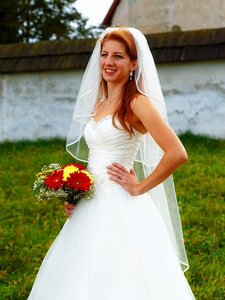 Mooie bruiloft boeket in handen van de bruid, en de kerk in de achtergrond. — Stockfoto