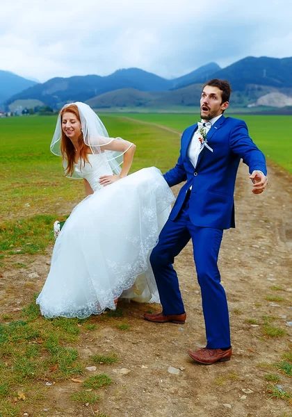 Sposo sbirciare sotto il suo abito da sposa - concetto di matrimonio divertente . — Foto Stock