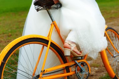 bride on orange bike in beautiful wedding dress with lace in landscape. wedding concept. clipart