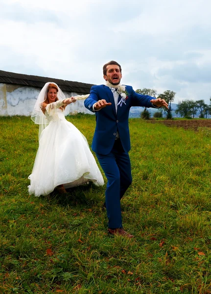 Braut zieht ihren Bräutigam mit Seil zu sich - lustiges Hochzeitskonzept. — Stockfoto