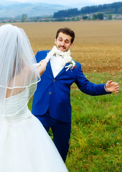 Noiva puxando seu noivo para ela com uma corda conceito de casamento engraçado . — Fotografia de Stock