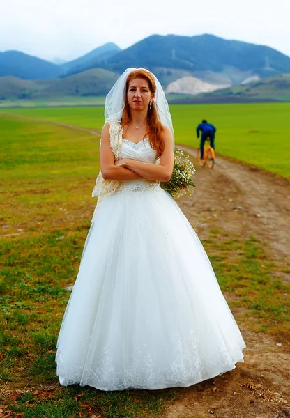 Sposa e sposo abbandonati che scappano in bicicletta - concetto di matrimonio divertente . — Foto Stock