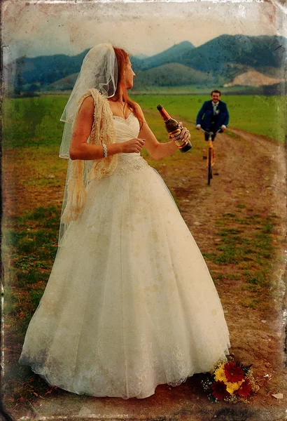 Braut mit Bierflasche und Bräutigam auf Fahrrad im Hintergrund - Hochzeitskonzept. Retro-Variante. — Stockfoto